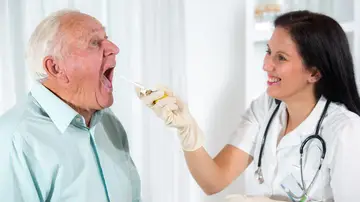 Doctora revisando la garganta de un paciente mayor Doctora revisando la garganta de un paciente mayor