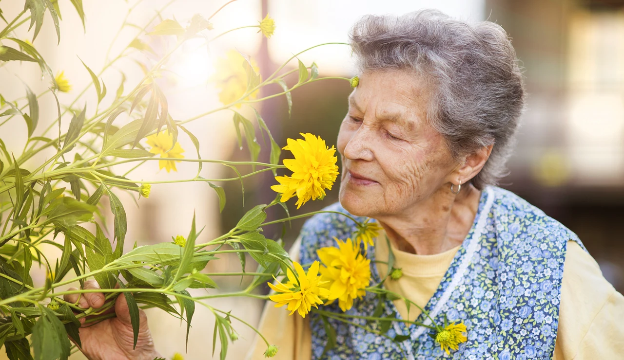 Mujer mayor oliendo una flor