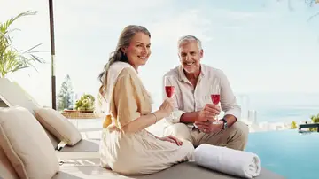 Pareja mayor disfrutando de una copa en una piscina Pareja mayor disfrutando de una copa en una piscina