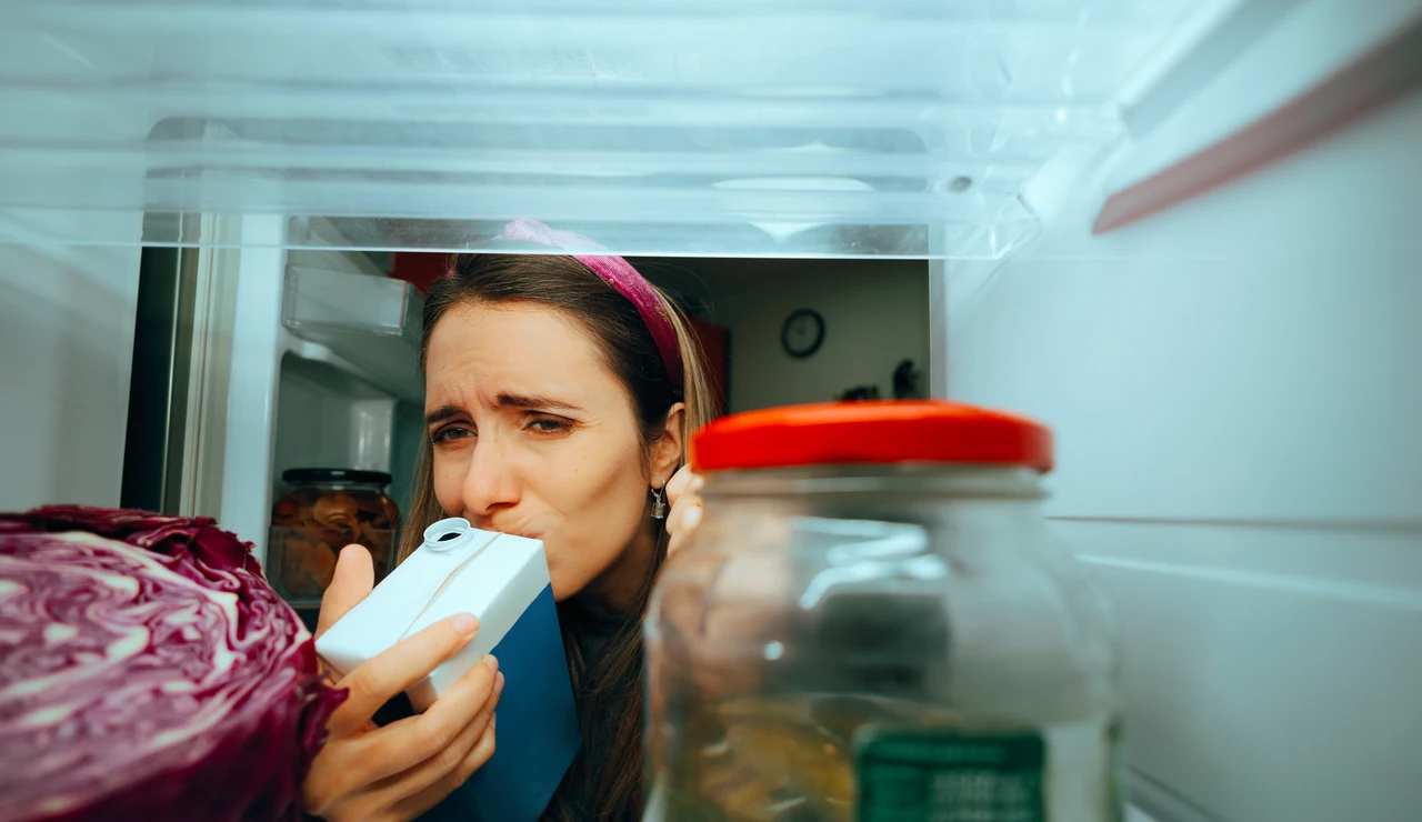 Mujer oliendo un cartón de leche