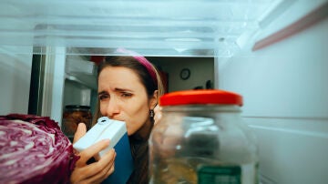 Mujer oliendo un cart&oacute;n de leche
