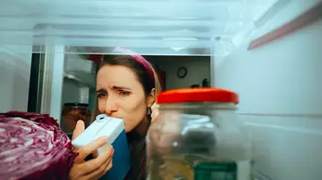 Mujer oliendo un cartón de leche Mujer oliendo un cartón de leche