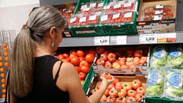 Una mujer comprueba la calidad de los tomates en un establecimiento