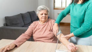 Mujer mayor tom&aacute;ndose la tensi&oacute;n