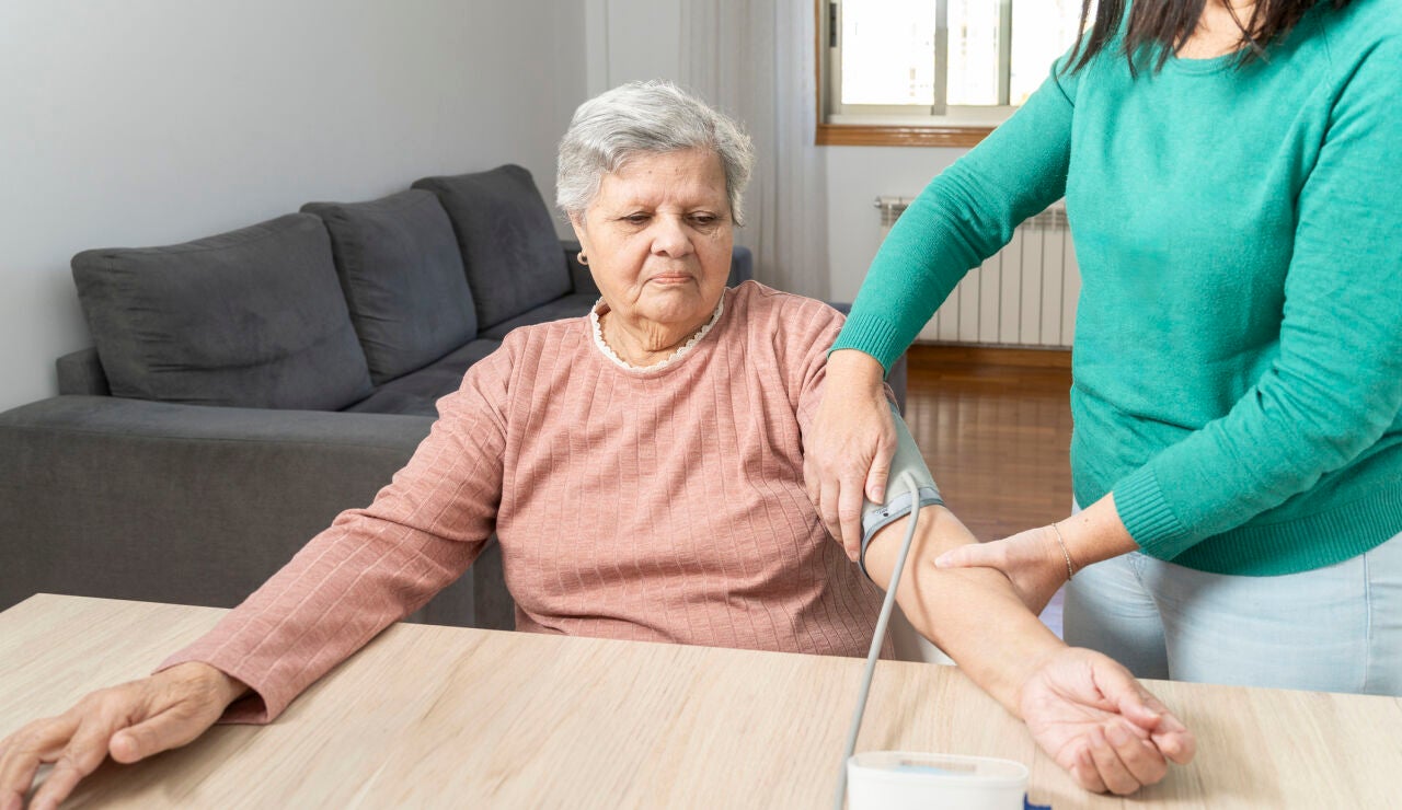 Mujer mayor tom&aacute;ndose la tensi&oacute;n
