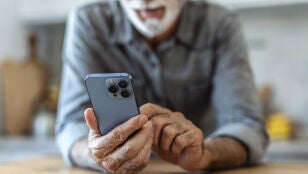 Hombre mayor consultando un tel&eacute;fono m&oacute;vil