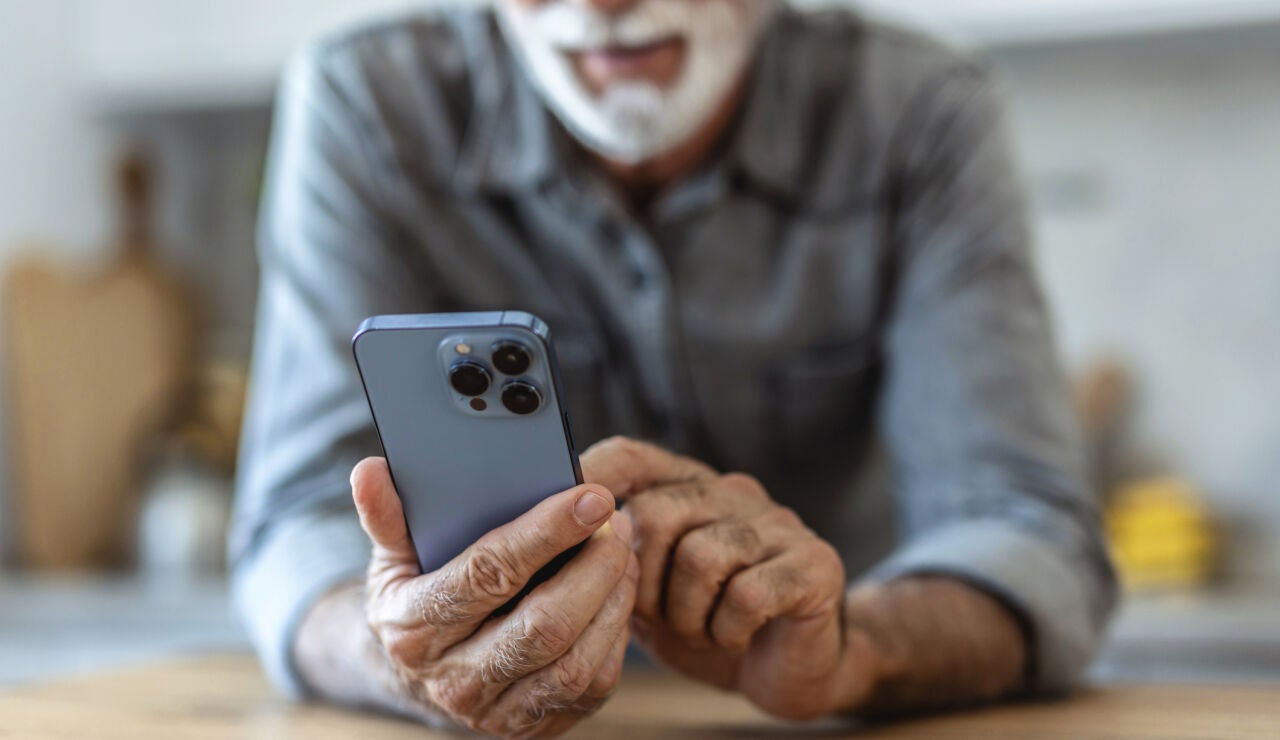 Hombre mayor consultando un tel&eacute;fono m&oacute;vil