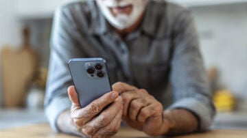 Hombre mayor consultando un tel&eacute;fono m&oacute;vil