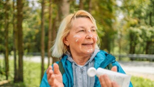 Mujer mayor aplic&aacute;ndose crema solar