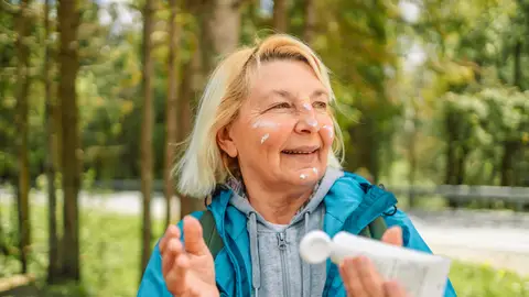 Mujer mayor aplicándose crema solar Mujer mayor aplicándose crema solar