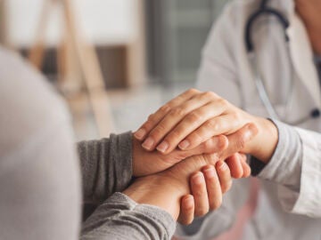 Mujer mayor d&aacute;ndose las manos con una doctora