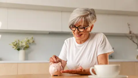 Mujer poniendo dinero en una hucha Mujer poniendo dinero en una hucha
