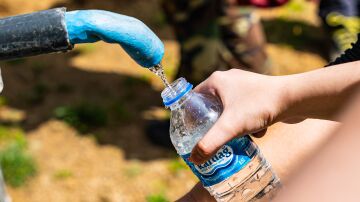 Personas llenando botellas de agua de una fuente exterior 