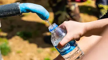 Personas llenando botellas de agua de una fuente exterior Personas llenando botellas de agua de una fuente exterior