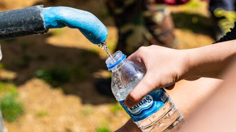 Personas llenando botellas de agua de una fuente exterior 