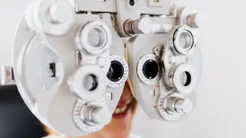 Primer plano de una mujer sometiéndose a un examen ocular usando un forómetro para probar la visión Primer plano de una mujer sometiéndose a un examen ocular usando un forómetro para probar la visión