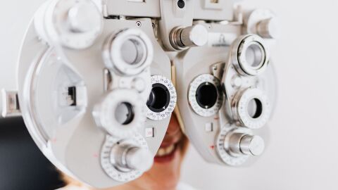 Primer plano de una mujer someti&eacute;ndose a un examen ocular usando un for&oacute;metro para probar la visi&oacute;n