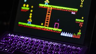 Primer plano de un port&aacute;til que muestra un videojuego retro con un teclado iluminado con luces de ne&oacute;n, capturando la experiencia nost&aacute;lgica del juego
