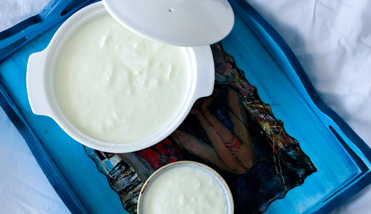 Vista superior de dos tazones de cerámica con yogur en una bandeja decorativa azul.
