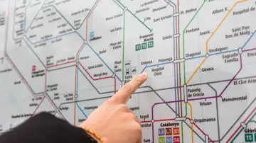 Una persona señala una estación en el detallado mapa del metro de Barcelona en interiores. Una persona señala una estación en el detallado mapa del metro de Barcelona en interiores.