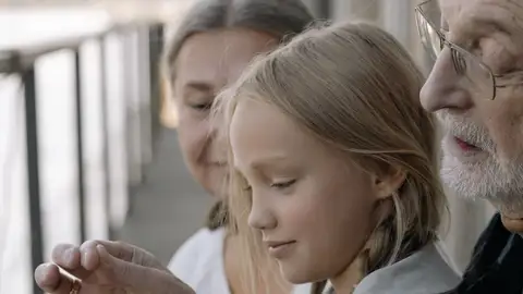 Un momento conmovedor de una nieta con sus abuelos en un porche soleado. Un momento conmovedor de una nieta con sus abuelos en un porche soleado.