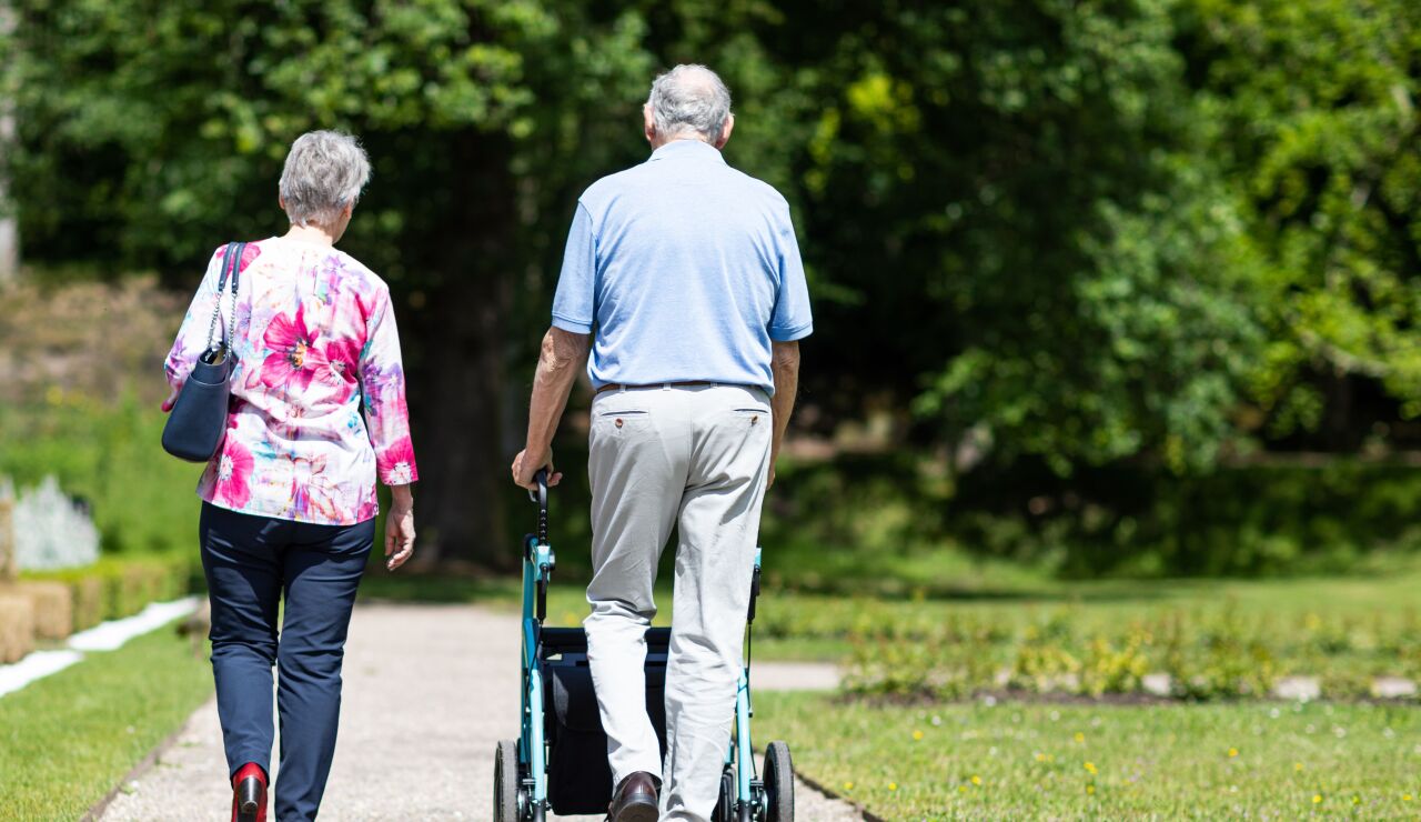 Pareja de ancianos caminando en un parque durante el verano, apoyando la movilidad y la uni&oacute;n.