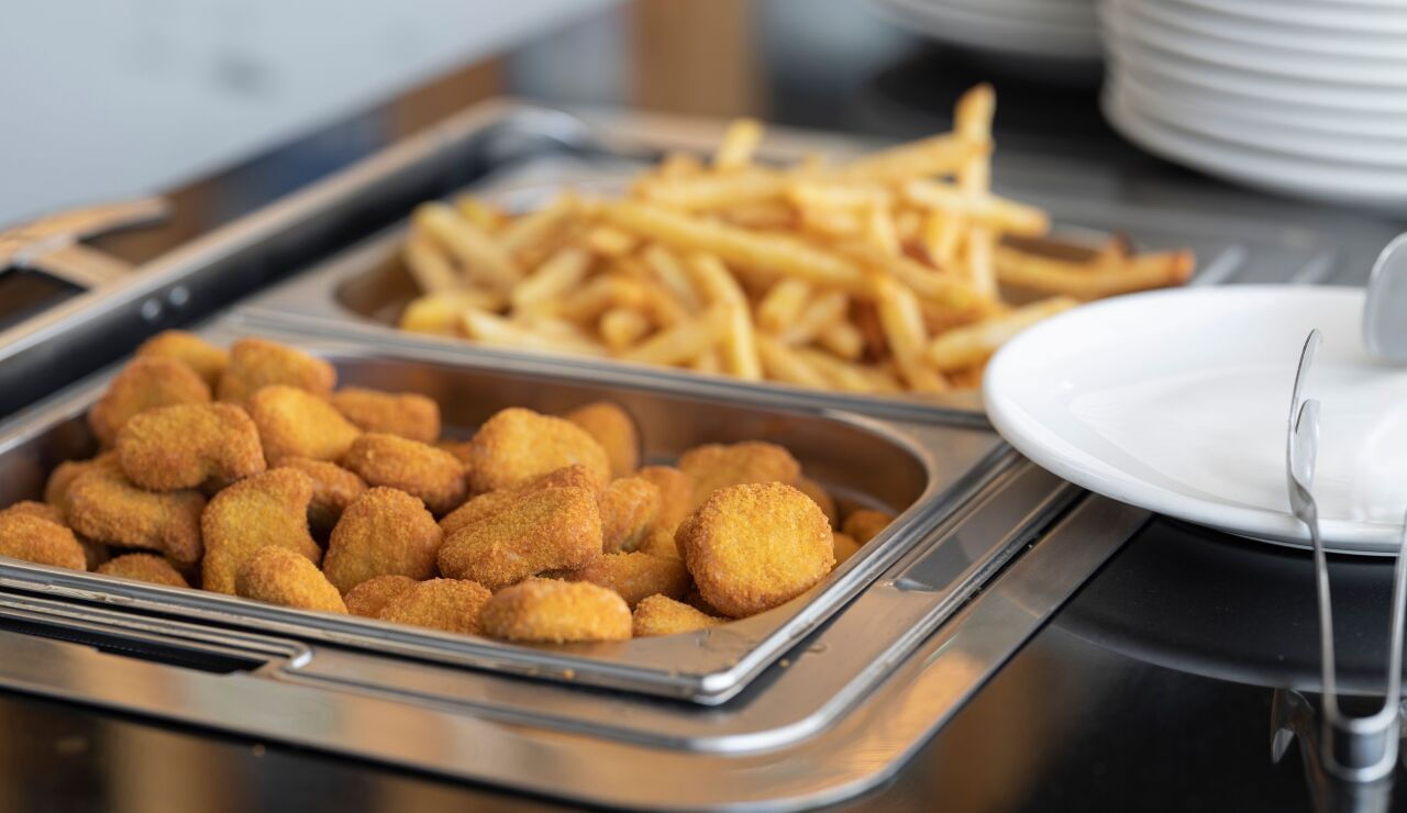 Nuggets crujientes y patatas fritas en un montaje de buffet, perfecto para im&aacute;genes de comida r&aacute;pida o catering.