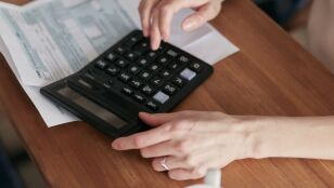 Una mujer usa una calculadora para gestionar las finanzas en casa, enfocada en la planificaci&oacute;n del presupuesto.