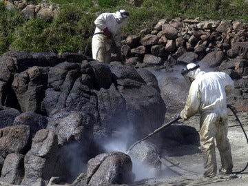 Unos operarios limpian la marea negra del Prestige