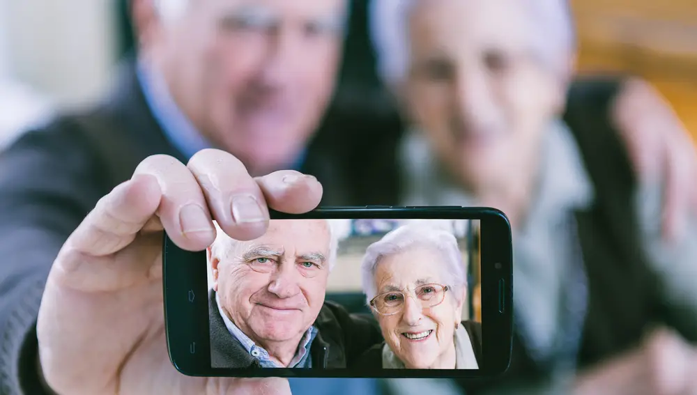 Dos personas mayores muestran una imagen tomada con su móvil.