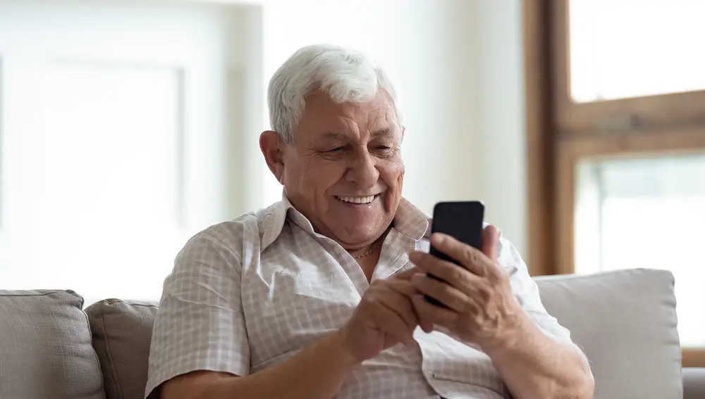 Hombre mayor feliz usando el móvil