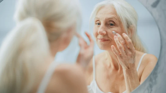Mujer mayor poniéndose crema Mujer mayor poniéndose crema