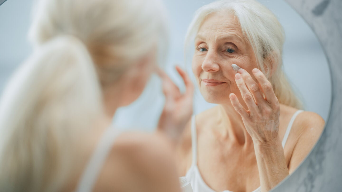 Mujer mayor poni&eacute;ndose crema