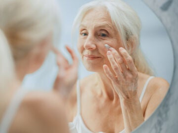 Mujer mayor poni&eacute;ndose crema