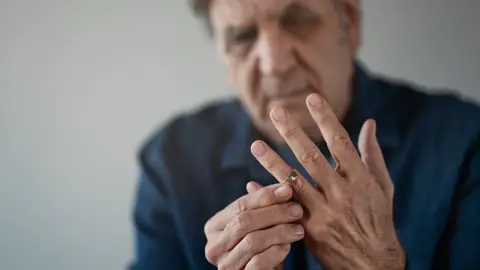 Divorcio: hombre mayor quitándose el anillo de casado Divorcio: hombre mayor quitándose el anillo de casado
