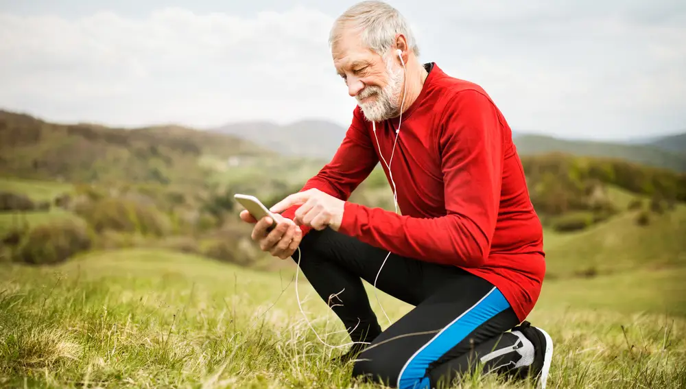 Hombre mayor haciendo ejercicio y consultando el móvil