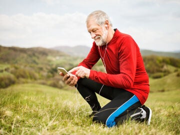Hombre mayor haciendo ejercicio y consultando el m&oacute;vil
