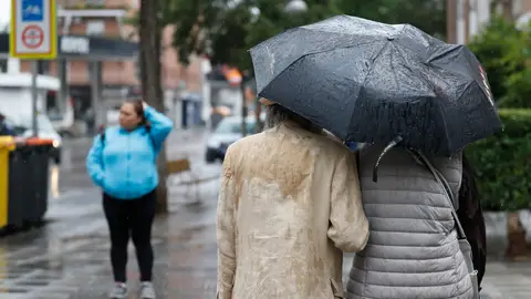 Dos personas se refugian de la lluvia con un paraguas Dos personas se refugian de la lluvia con un paraguas