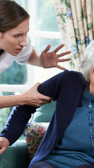Una cuidadora agarra fuertemente a una persona mayor