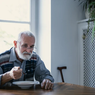 Hombre mayor triste comiendo