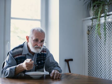 Hombre mayor triste comiendo