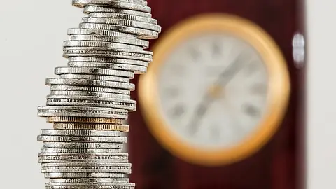 Monedas, dinero apilado con reloj de fondo Monedas, dinero apilado con reloj de fondo