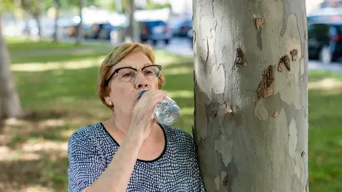Mujer mayor bebiendo agua en un parque Mujer mayor bebiendo agua en un parque