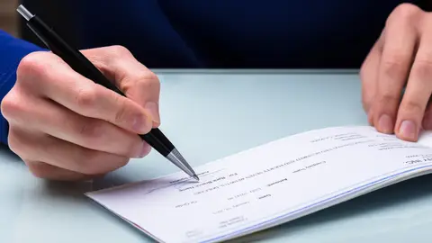 Una persona firmando un cheque Una persona firmando un cheque