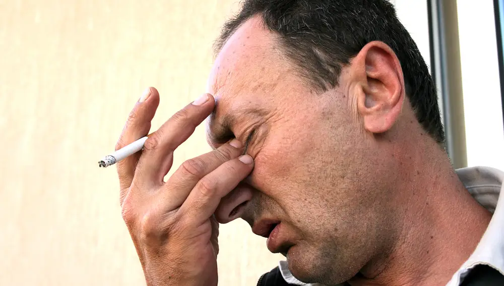 Hombre fumando y con dolor de cabeza
