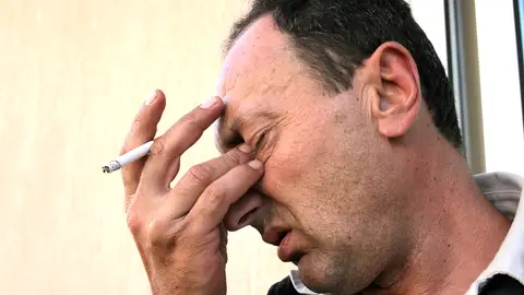 Hombre fumando y con dolor de cabeza Hombre fumando y con dolor de cabeza