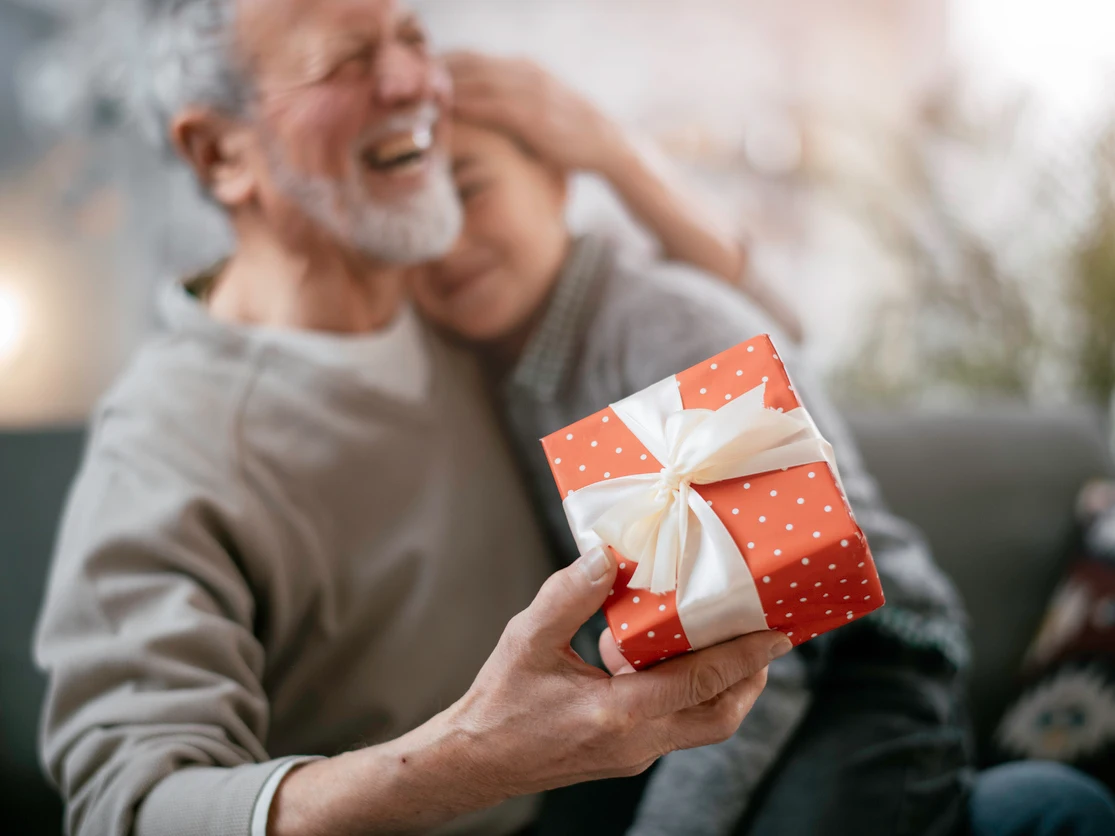 El abuelo dando una caja de regalo a una nieta feliz