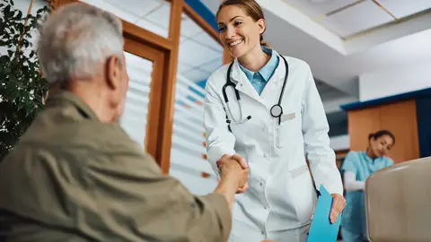 Un médico saluda a una persona mayor en la sala de espera Un médico saluda a una persona mayor en la sala de espera