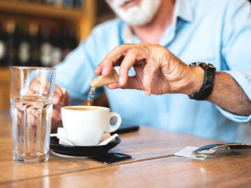 Hombre vertiendo az&uacute;car en el caf&eacute;