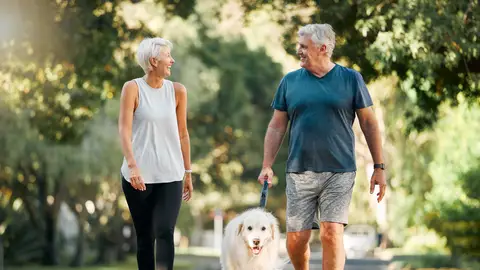 Pareja dando un paseo mientras pasea un perro Pareja dando un paseo mientras pasea un perro